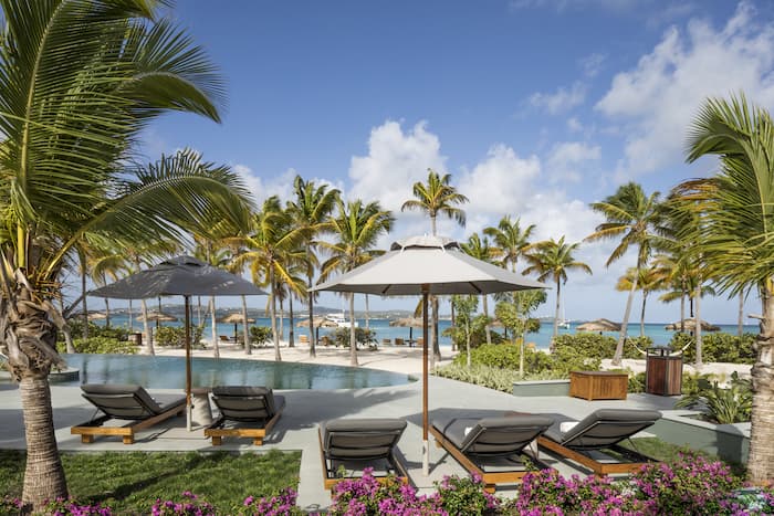 Deck chairs and pool with a beach view