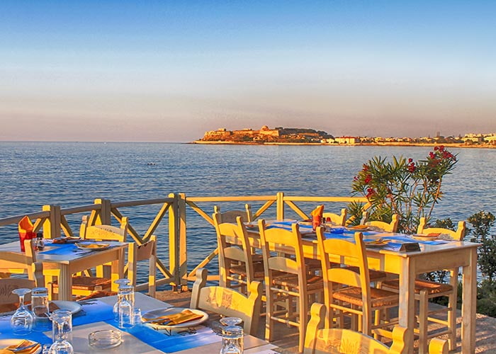 Traditional outdoor restaurant on terrace with sea view at street village restaurant, Crete, Greece.
