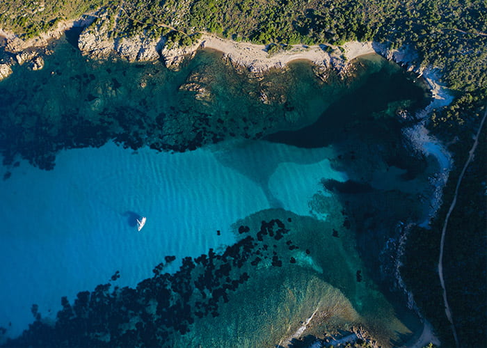 Aerial view of a sailing boat floating on Maddalena Archipelago National Park, Sardinia, Italy