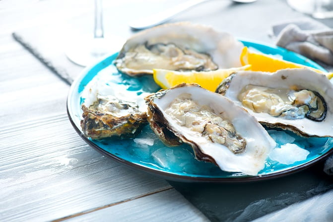 Oysters on a small plate with slices of lemon