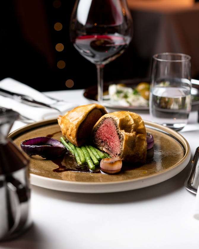 Beef wellington with gravy and a glass of red wine