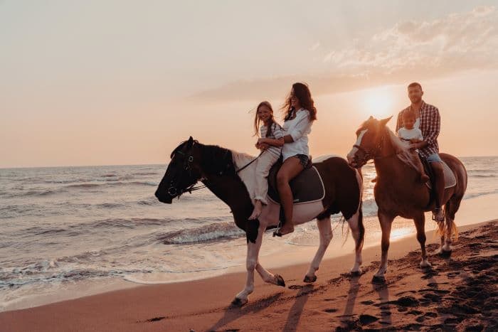 Family horse riding on beach